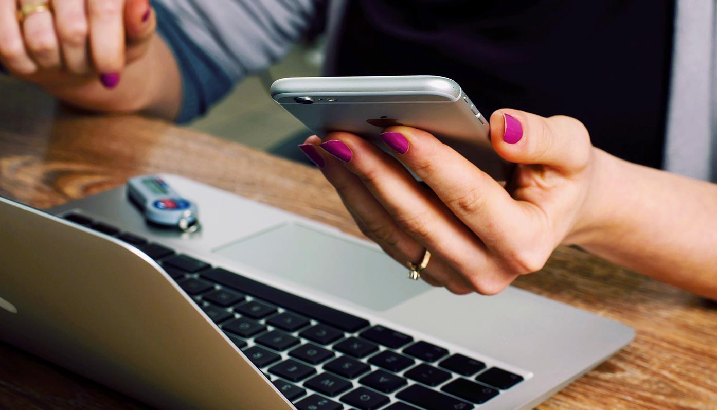 Frau arbeitet mit Computer und Handy